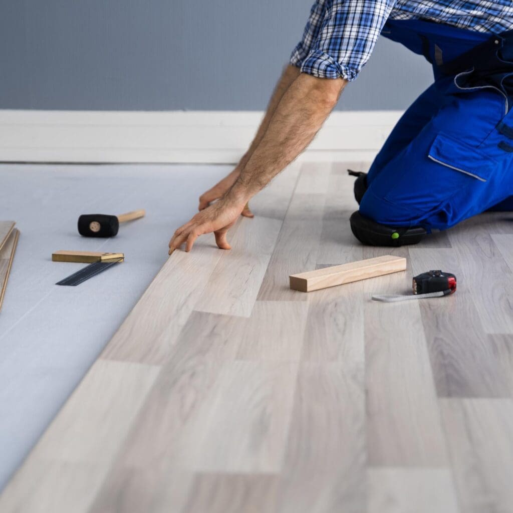 floor expert in blue clothes installing a wooden tile floor