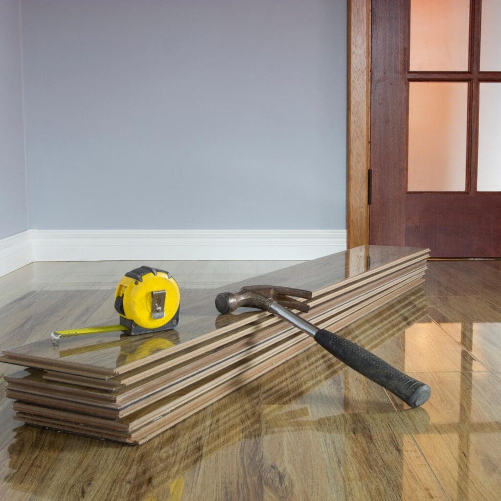 glossy wooden floor panels with hammer and tape measure placed on top on a newly installed floor