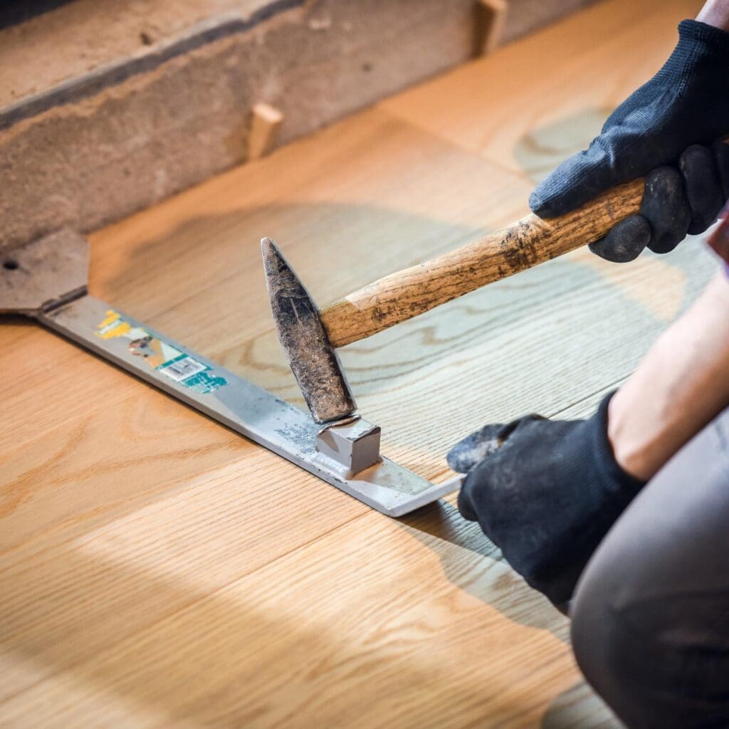 floor expert using a heavy duty pull bar during tile floor installation