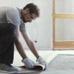 Professional contractor removing an old linoleum flooring: home renovation concept