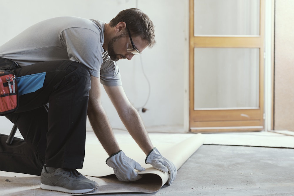 Professional contractor removing an old linoleum flooring: home renovation concept